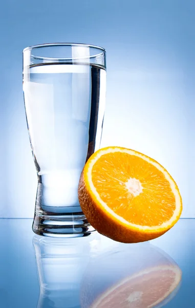 Glass of water and orange on a blue background — Stock Photo, Image