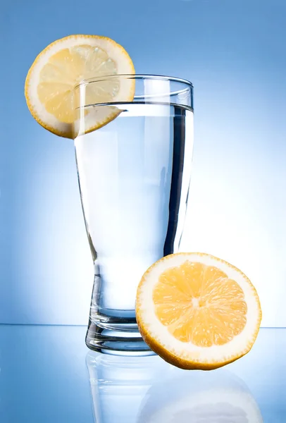 Glass of water and lemon on a blue background — Stock Photo, Image