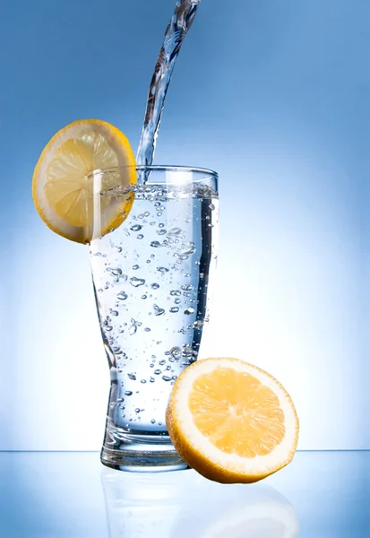 Mineral water glass with lemon on a blue background — Stock Photo, Image
