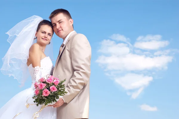 Junge glückliche Braut und Bräutigam am Hochzeitstag auf einem Hintergrund Himmel w — Stockfoto