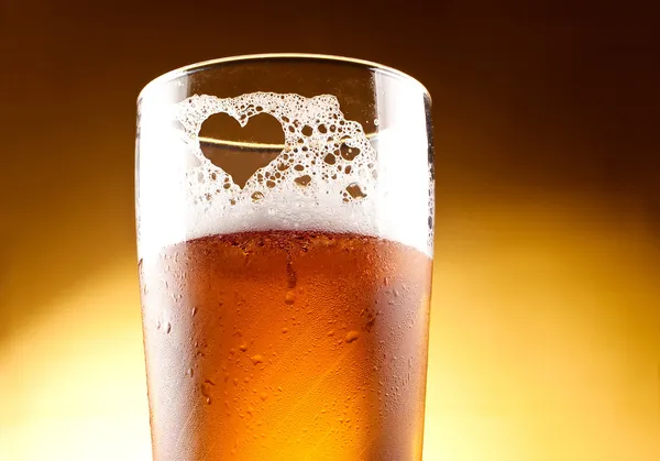 Стакан пива с сердцем, представленным пеной крупным планом Лицензионные Стоковые Фото