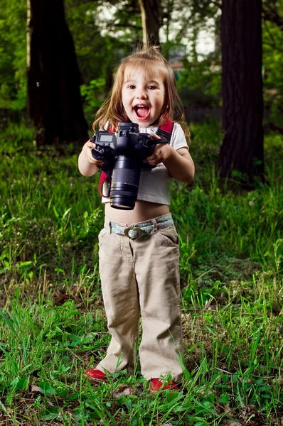 Amusing little girl takes pictures a professional camera — Stock Photo, Image