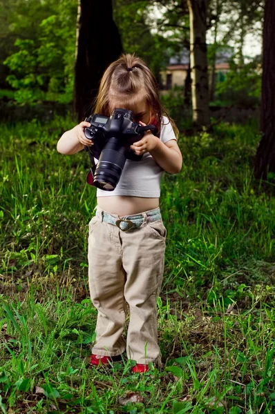 Amusant petite fille prend des photos d'un appareil photo professionnel — Photo