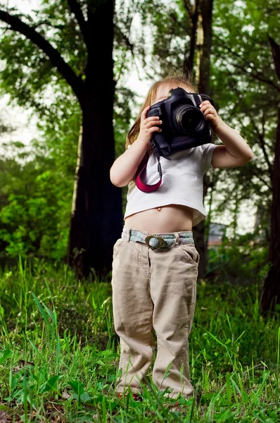Zábavná malá holčička fotí profesionální fotoaparát — Stock fotografie