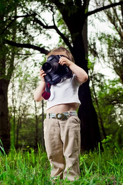 Забавная маленькая девочка фотографирует профессиональную камеру — стоковое фото