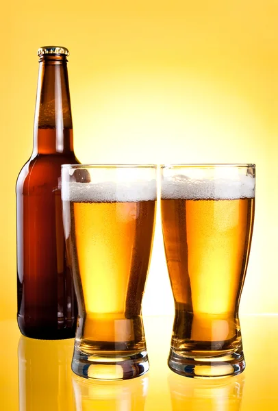 Two glasses and Bottle of fresh light beer on yellow background — Stock Photo, Image