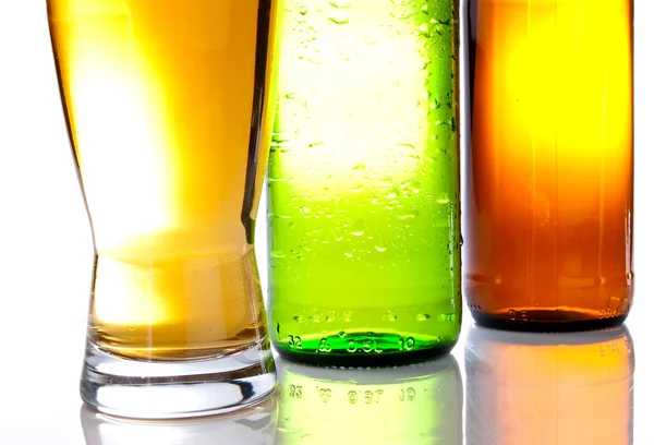 Parte inferior das garrafas marrom e verde com um copo cheio de cerveja — Fotografia de Stock