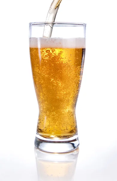 Светлое пиво выливается в стекло на белом фоне — стоковое фото