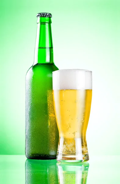Bottiglia verde raffreddata con condensa e un bicchiere di birra lager o — Foto Stock