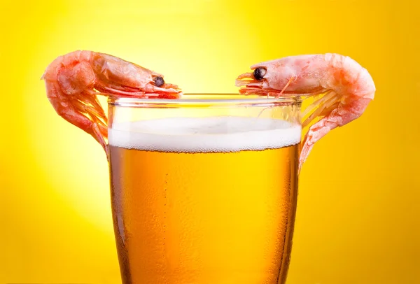 Two Cooked Shrimp in a glass of beer with foam on a yellow backg — Stock Photo, Image