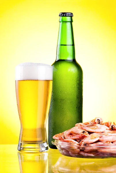 Green bottle of beer with a condensate, a glass and a plate of b — Stock Photo, Image