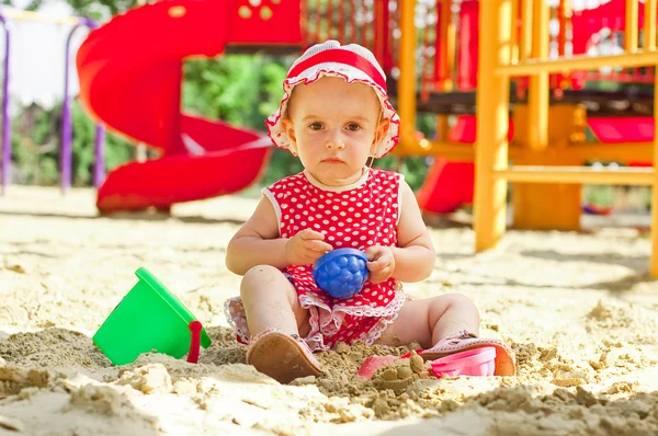 Belle petite fille en vêtements rouges, jouant dans un bac à sable — Photo