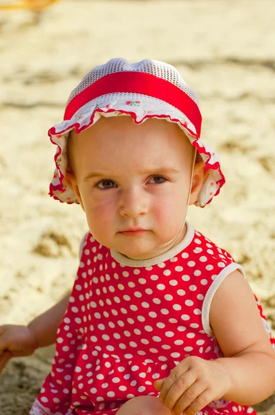 Schönes kleines Mädchen in roter Kleidung, das in einem Sandkasten spielt — Stockfoto