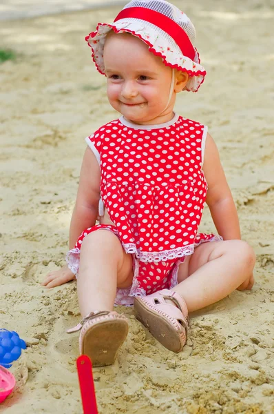Beautiful little girl in red clothes, playing in a sandbox — Stock Photo, Image