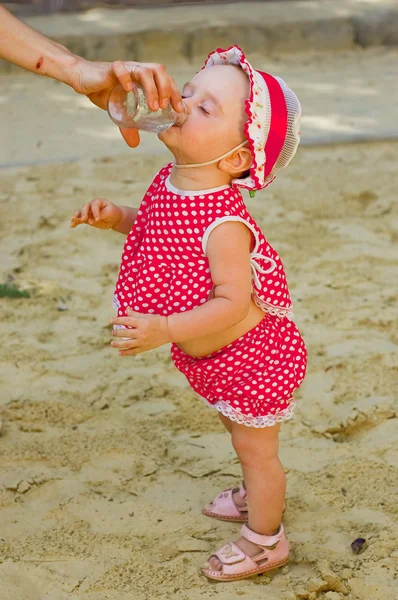 Kum havuzunda oynamayı kırmızı giysili güzel küçük bir kız — Stok fotoğraf
