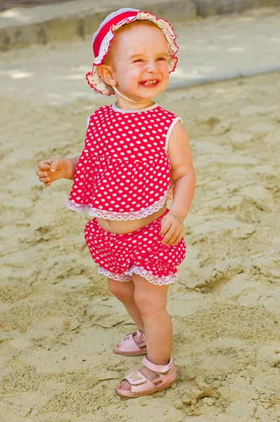 Kum havuzunda oynamayı kırmızı giysili güzel küçük bir kız — Stok fotoğraf