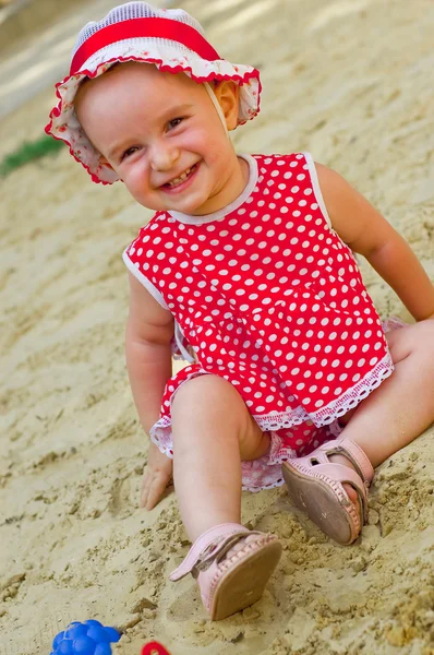 Hermosa niña con ropa roja, jugando en una caja de arena —  Fotos de Stock