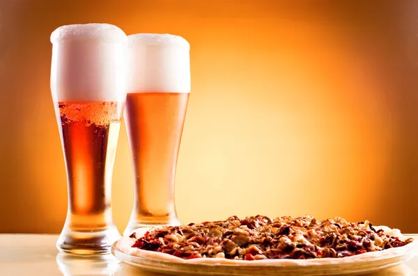 Dos vasos de cerveza y pizza sobre fondo amarillo — Foto de Stock