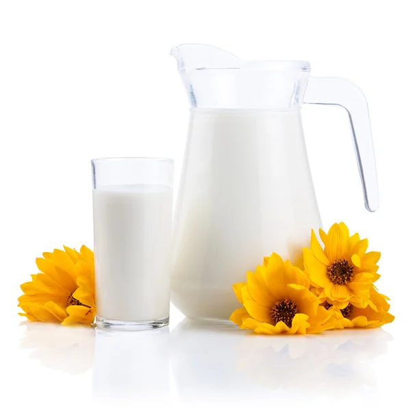 Kancsó és pohár friss tej és elszigetelt fehér sárga virágok — Stock Fotó