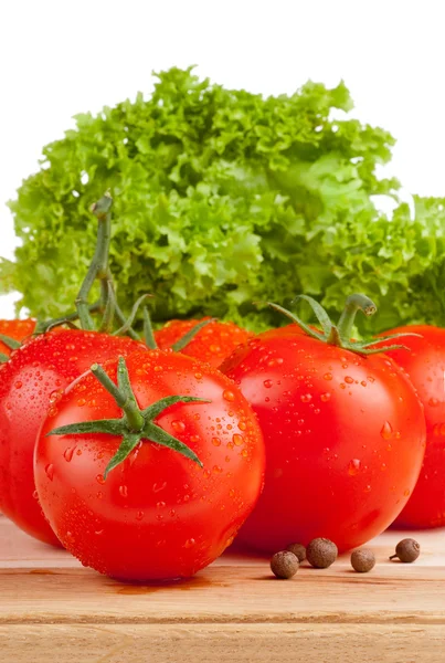 Färska våta tomater, kryddpeppar och sallad på en cutting board trä — Stockfoto