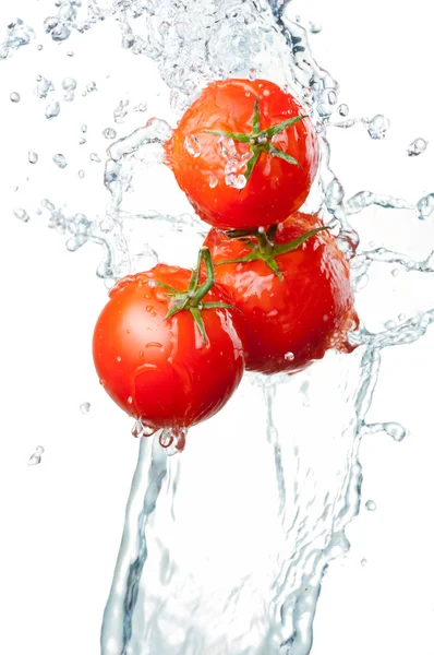 Três tomates vermelhos frescos em respingo de água Isolado em branco ba — Fotografia de Stock