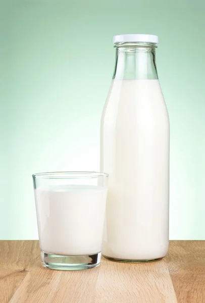 Bottle of fresh milk and glass is wooden table on a green backgr — Stock Photo, Image