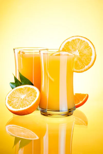 Two Glasses of Fresh Orange juice, half oranges and the leaves o — Stock Photo, Image