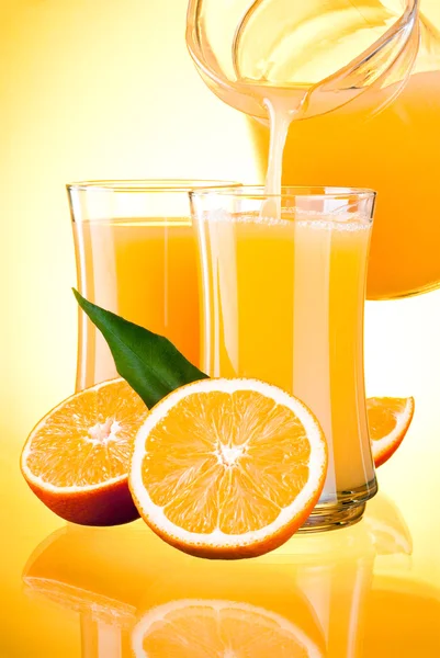 Juice to pour from pitcher, Oranges with leaves on yellow backgr — Stock Photo, Image