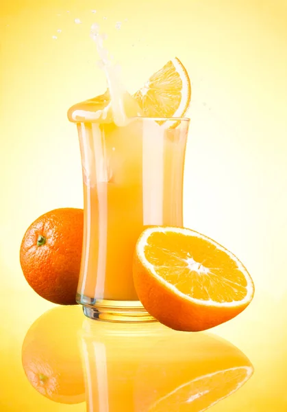 Splashing suco de laranja fresco no fundo amarelo — Fotografia de Stock