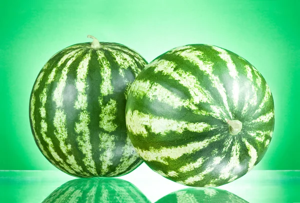Två vattenmeloner isolerad på en grön bakgrund — Stockfoto