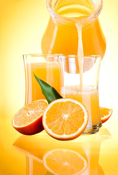 Juice to pour from pitcher, Oranges with leaves on yellow backgr — Stock Photo, Image