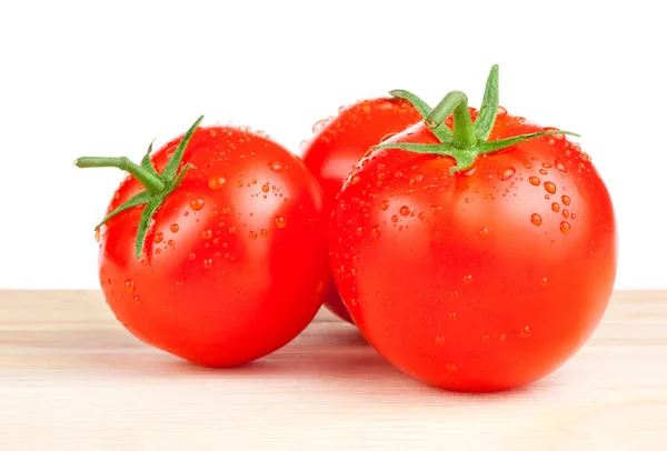 Tre färska våta tomater på en trä skärbräda isolerad på w — Stockfoto