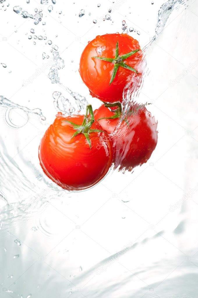 Three Fresh red Tomatoes in splash of water Isolated on white ba