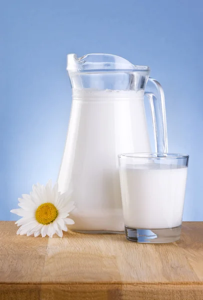 Karaf verse melk, glas en een kamille bloemen is houten tafel — Stockfoto