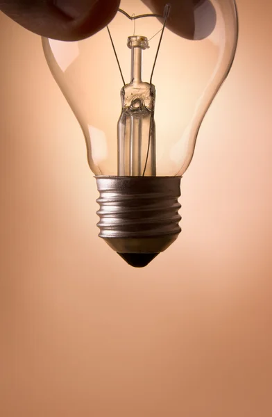 stock image Hand holding light bulb on the beige background