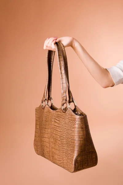 stock image Hand holding handbag on the beige background