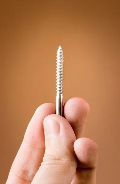 stock image Hand holding screw on the beige background