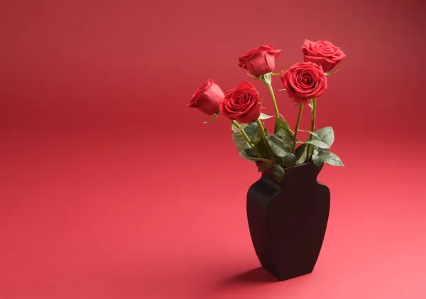 Cinque rose nel vaso sullo sfondo rosso — Foto Stock