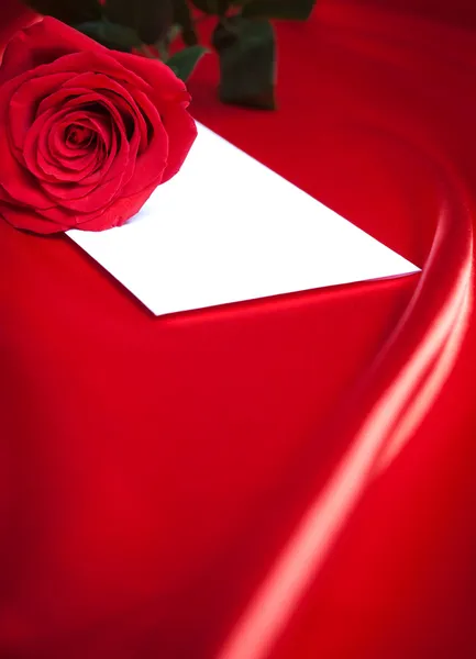 Envelop en rode rose over zijde achtergrond — Stockfoto