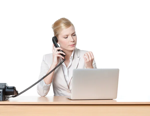 Young businesswoman sitting at a desk with phone handset — Stock Photo, Image