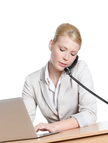 Young business woman sitting at a desk with phone handset — Stock Photo, Image