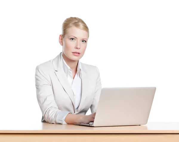 Giovane donna d'affari seduta a una scrivania con computer portatile, isolata — Foto Stock