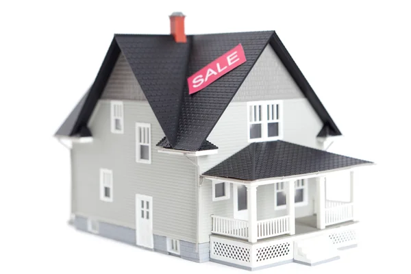 Модель дома с вывеской на продажу, изолированная — стоковое фото