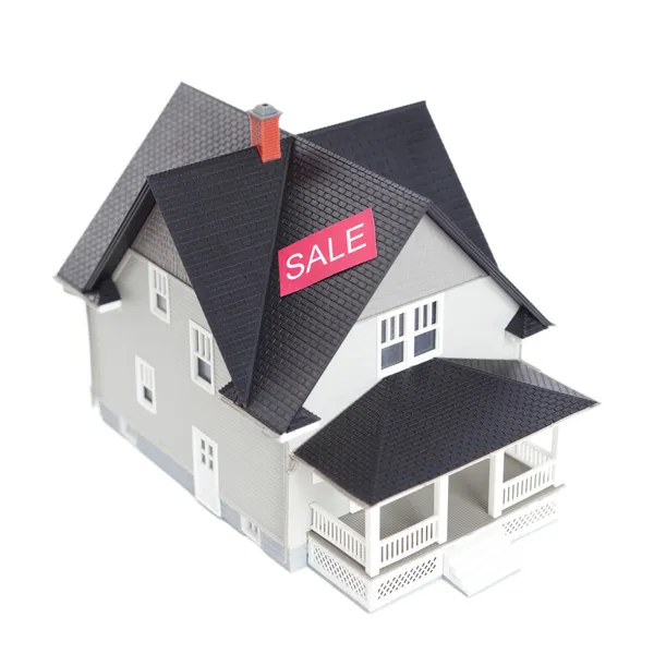 Модель дома с табличкой продажи, изолированная на белом — стоковое фото