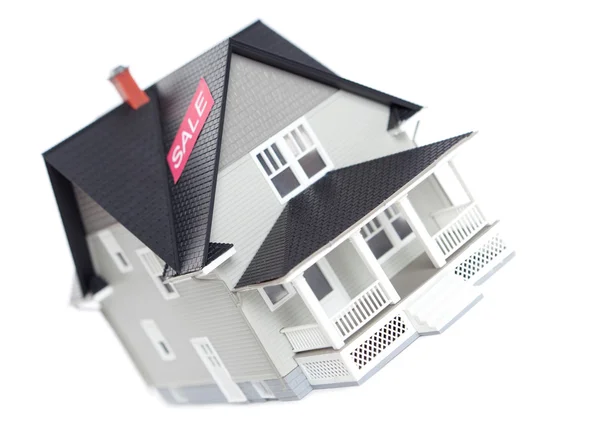 Модель дома с табличкой продажи, изолированный — стоковое фото