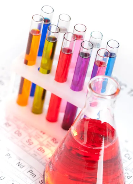 Group of test tubes and flask on the periodic table — Stock Photo, Image