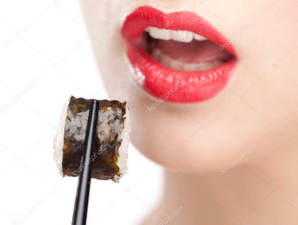 Brunette woman holding sushi with a chopsticks, closeup