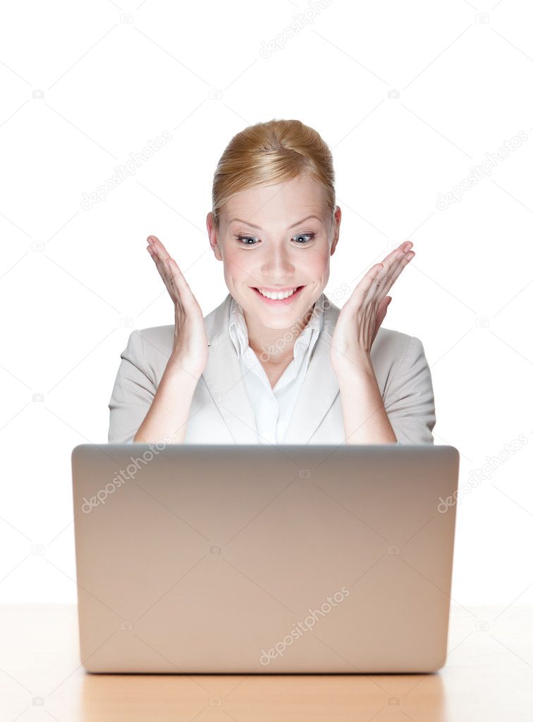 Happy young business woman sitting at a desk with laptop
