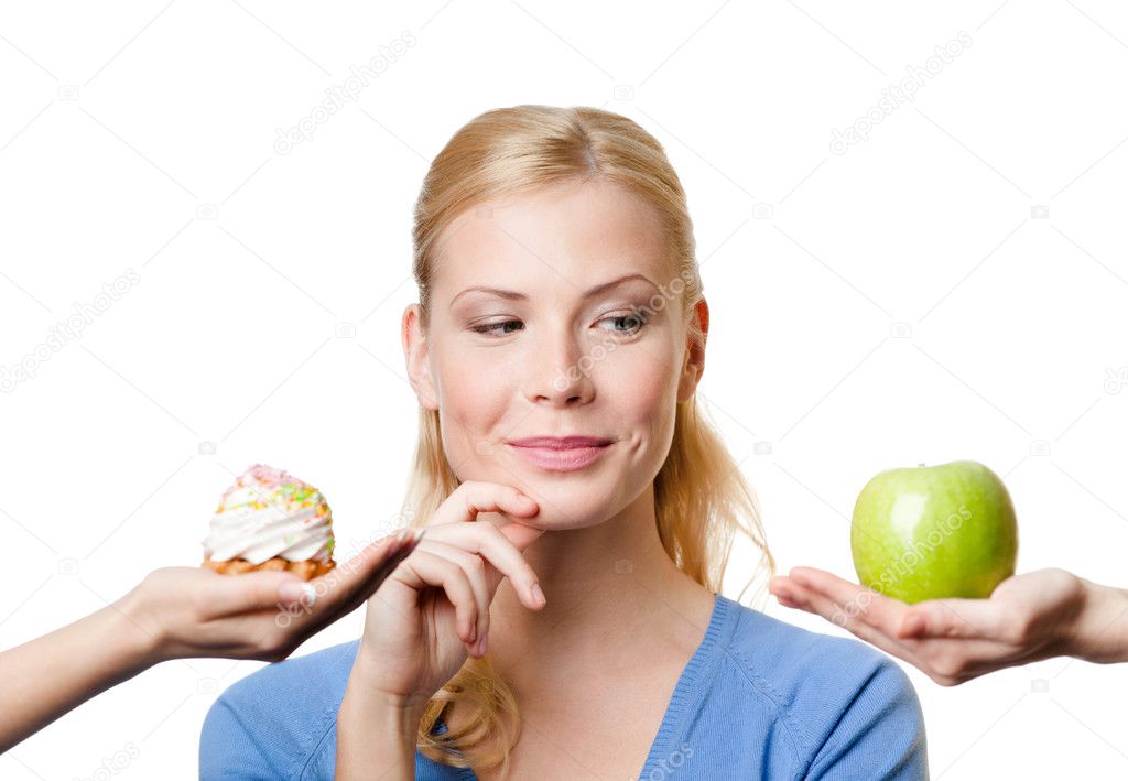 Young woman makes a choice between cake and apple