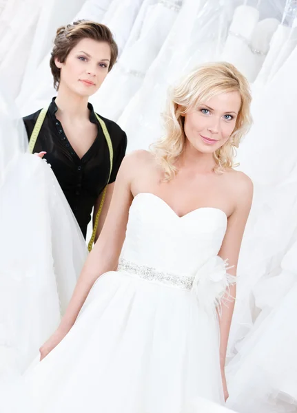 Winkelbediende stelt een andere jurk voor de bruid — Stockfoto